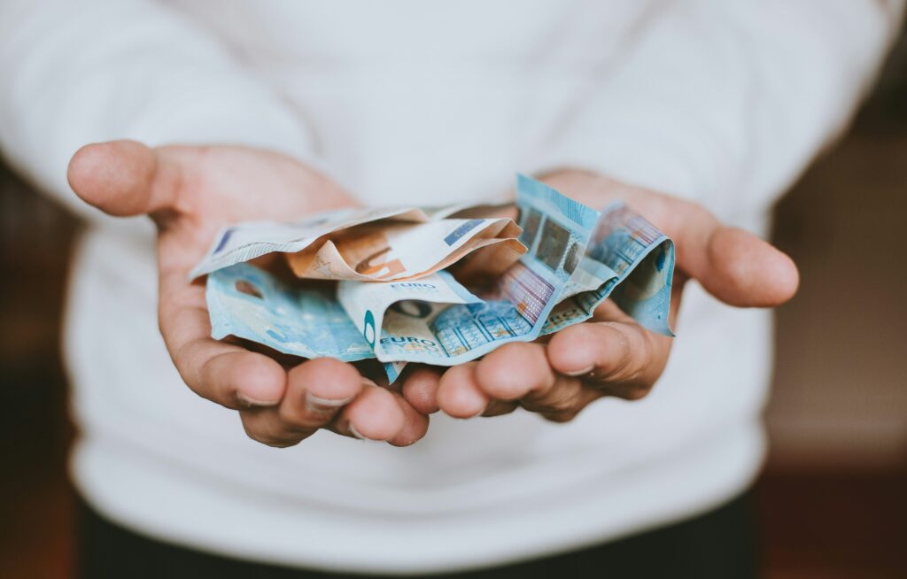 Zwei geöffnete Hände halten mehrere Euro-Banknoten, die locker gefaltet sind. Das Bild vermittelt Großzügigkeit oder den Erhalt von zusätzlicher finanzieller Anerkennung. SFN-Zuschläge (Sonn-, Feiertags- und Nachtzuschläge) verweisen hier auf den Anspruch der Arbeitnehmenden auf steuerfreie oder begünstigte Zuschläge als Ausgleich für besondere Arbeitszeiten und die damit verbundene Wertschätzung ihrer Leistung.