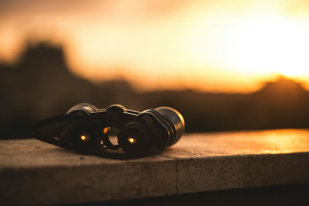 Fernglas im Sonnenuntergang, symbolisiert den Ausblick auf kommende Änderungen im Faktorverfahren und die geplante Abschaffung der Steuerklassen 3 und 5 bis 2030. Ideal für Inhalte, die sich mit zukünftigen Entwicklungen in der Lohnbuchhaltung und Steuerpolitik befassen. Verbindung von Weitsicht und Vorbereitung für Unternehmen und Steuerexperten.