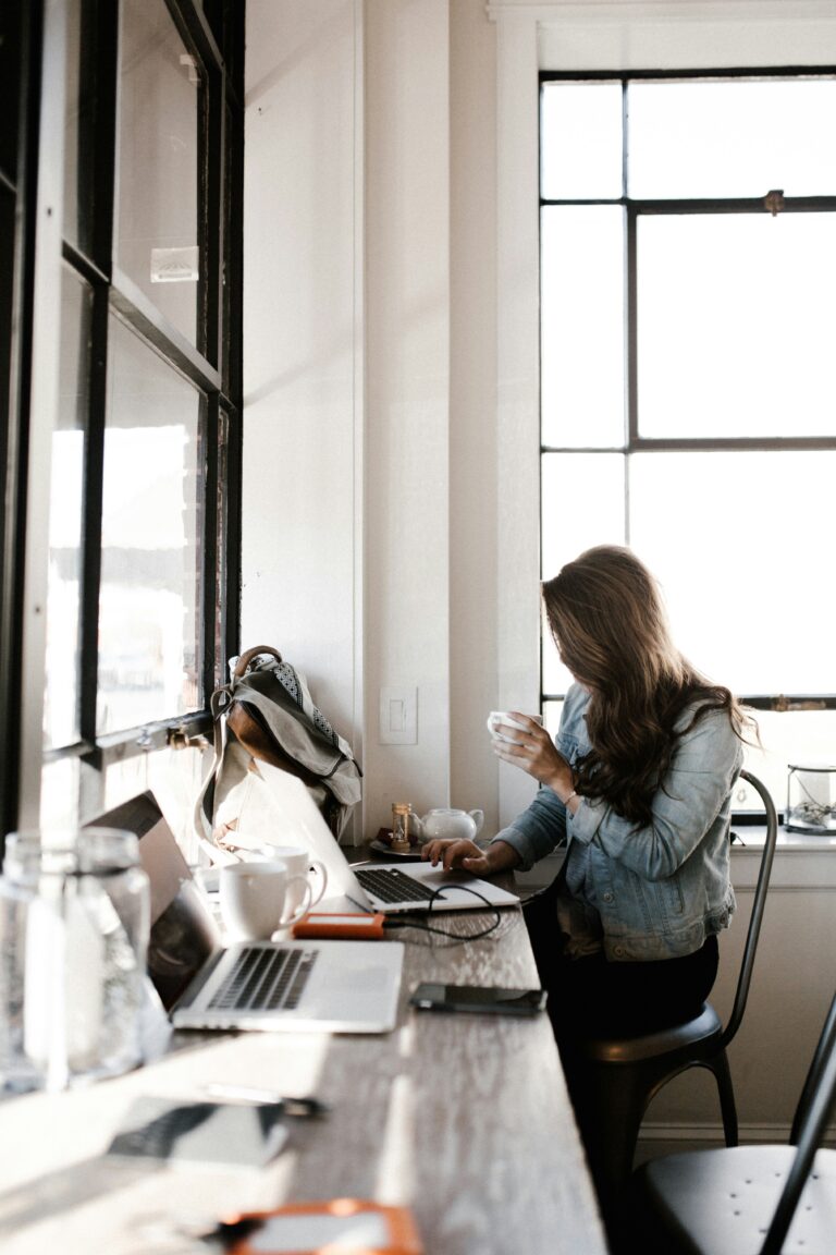 Eine junge Frau arbeitet mit ihrem Laptop in einem Café, symbolisiert die flexible Arbeitsweise von Freelancern und Selbstständigen. Das Bild steht exemplarisch für das Thema Scheinselbstständigkeit und die Abgrenzung zwischen freier Tätigkeit und abhängiger Beschäftigung. Es eignet sich ideal für Beiträge zur rechtlichen Einordnung, den Risiken für Unternehmen und die Bedeutung der korrekten Lohnabrechnung.